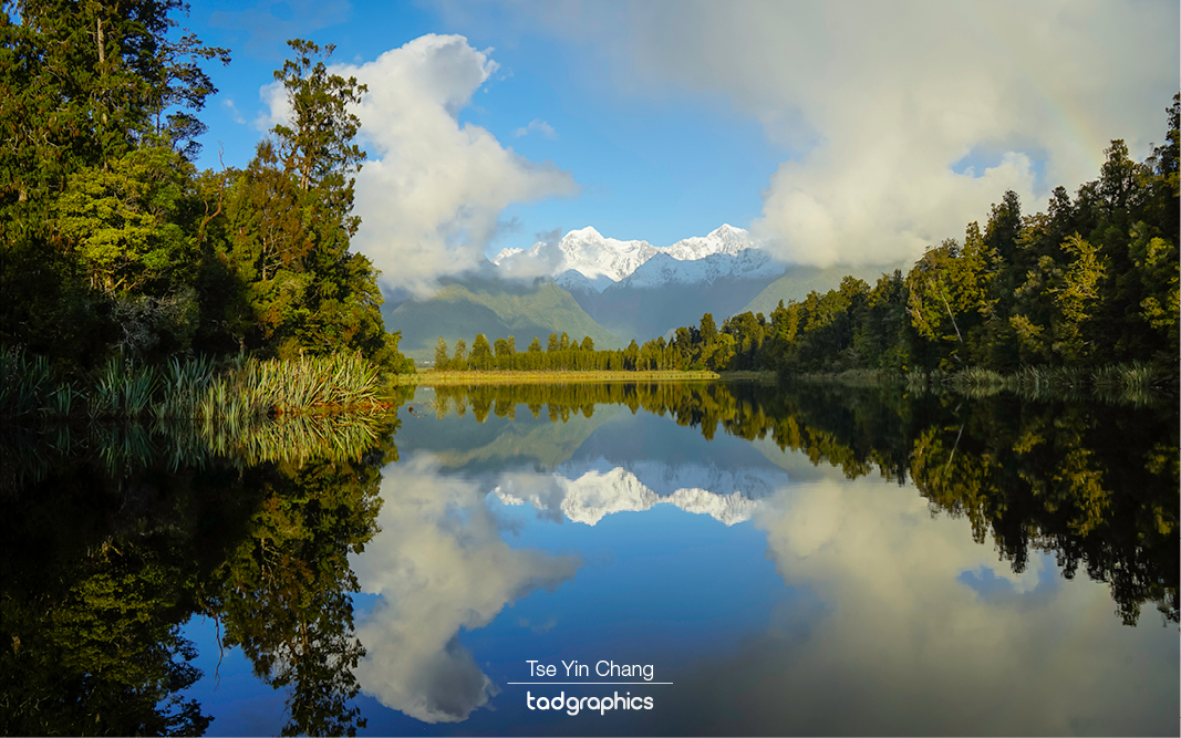 Waters in Lake Matheson reflect the peaks of both Mount Cook and Mount Tasman, while pine trees reached all the way to its shores